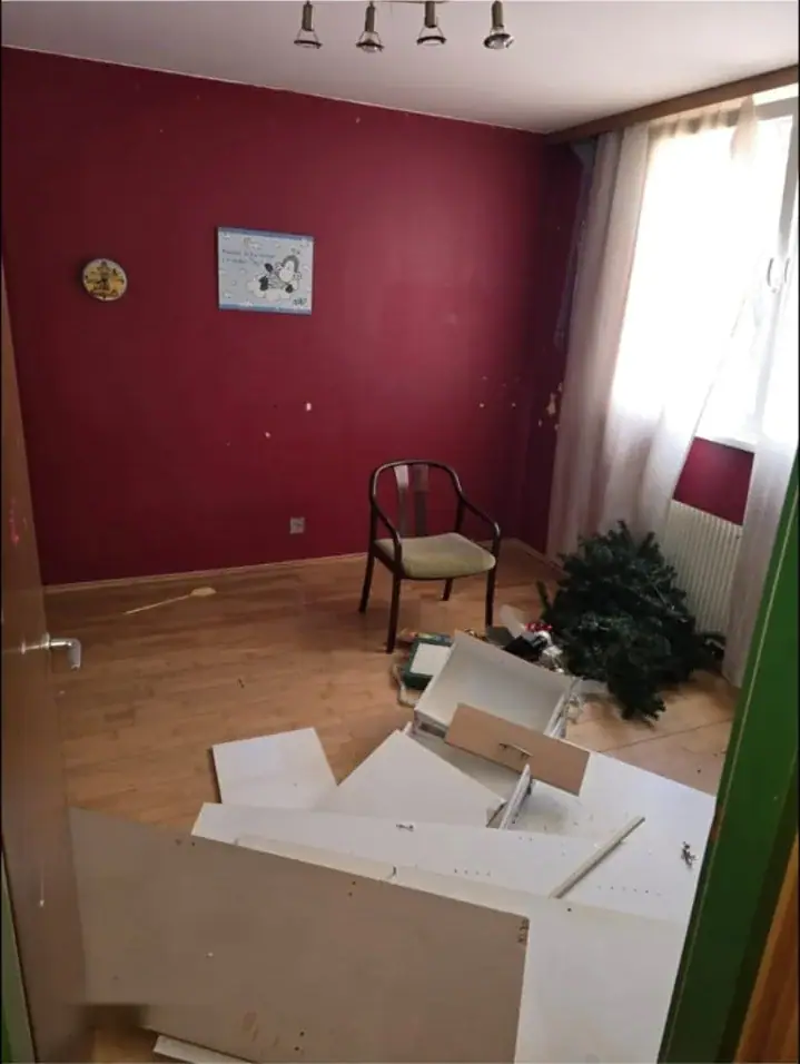 Zimmer mit dunkelroter Wand und zerlegten Möbelteilen am Boden
